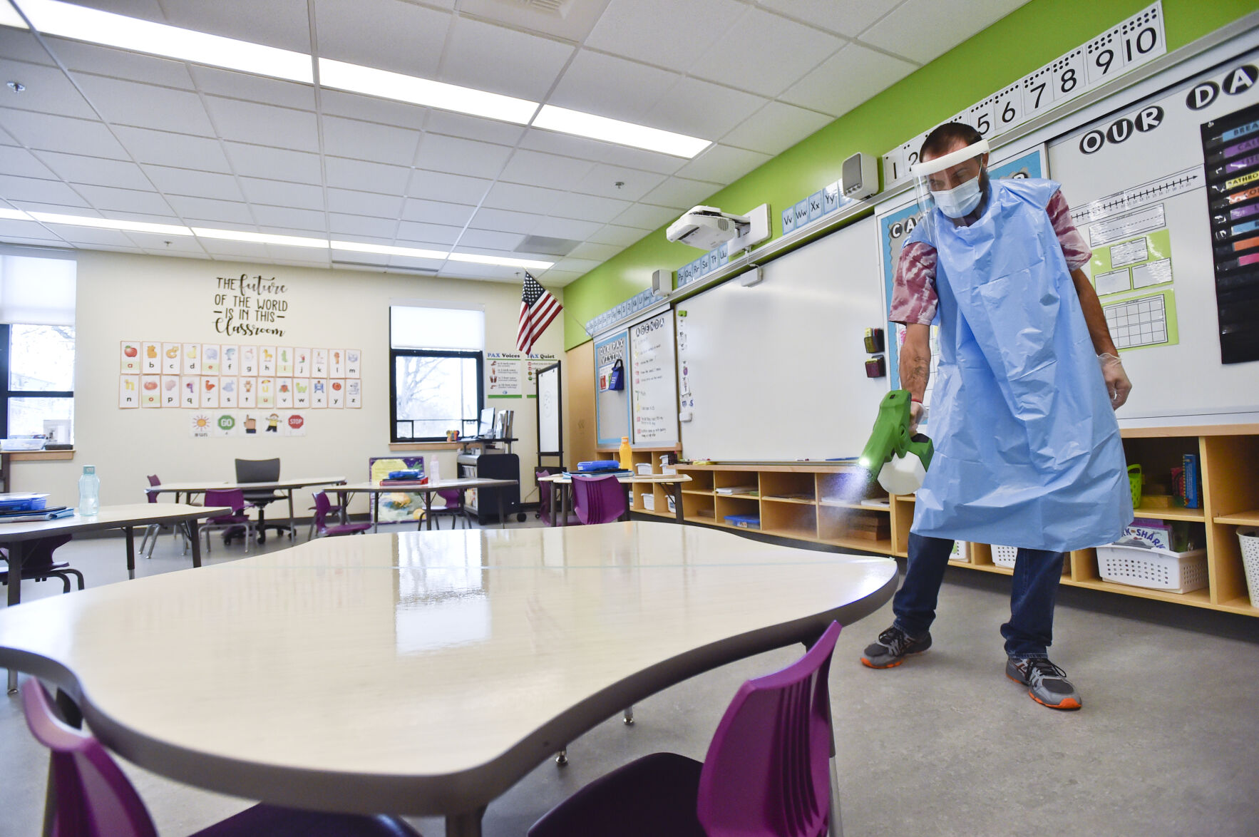 Bryant Elementary School custodian Mike Higgins uses a electrostatic sprayer